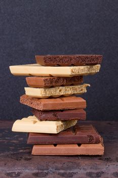 stack of different kind porous chocolate pieces on a dark background.