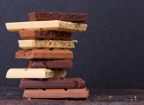 stack of different kind porous chocolate pieces on a dark background.