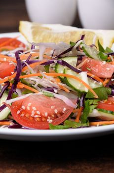Salad of white and blue chopped cabbage, carrots, cucumber, tomato dressed with oil, lemon, sesame