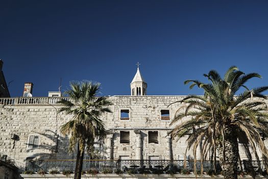 Palm trees and antique walls of the Diocletian palace in the city of Split, Croatia