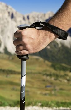 Close-up of a hand with walking pole against mountain in the distance