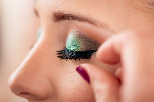 Makeup artist applying the false eyelashes to model. Close up. 