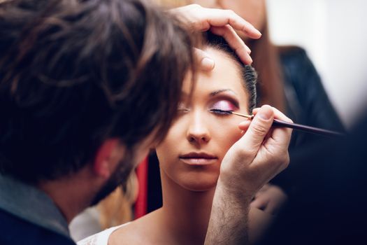 Close up of a makeup man artist getting eyeliner to model.