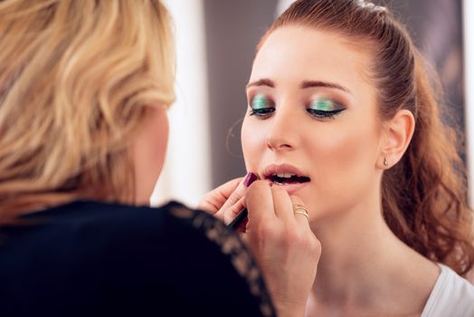 Close up of a make-up artist contouring lips to model.  