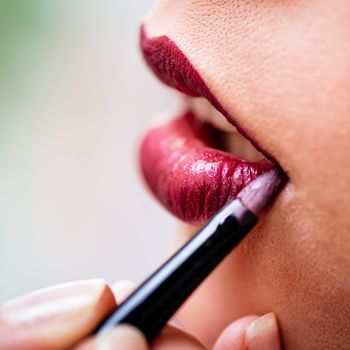 Close up of a makeup artist applying perfect red lipstick to model.