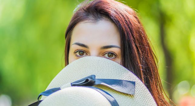 woman is covering her face with a hat