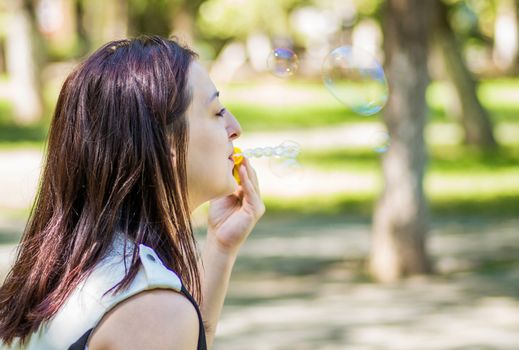 young woman blowing soap bubbles in the park