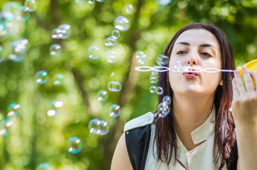 young woman blowing soap bubbles in the park