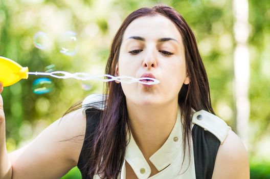 young woman blowing soap bubbles in the park