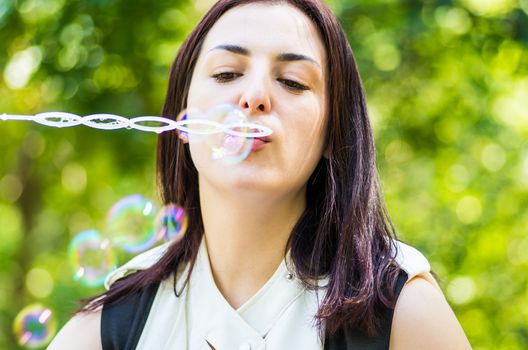 young woman blowing soap bubbles in the park