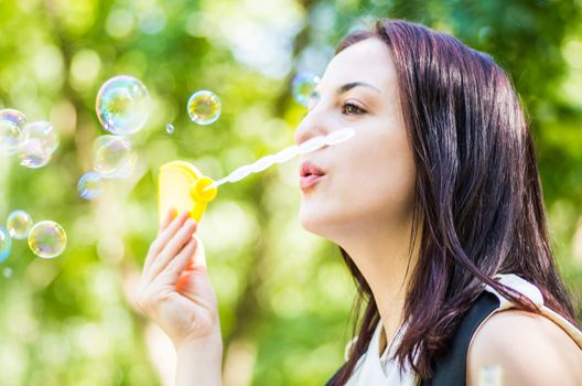 attractive woman blowing soap bubbles in the park