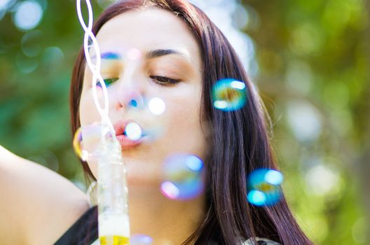 young attractive caucasian woman blowing soap bubbles