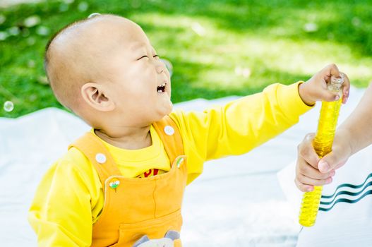 a baby sits on the mat in the park laughing