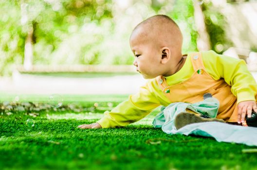 baby chasing soap bubbles on the mat outdoors