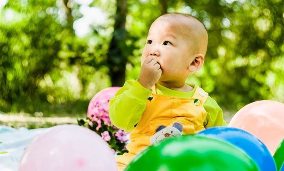 baby is playing with balloons in the park