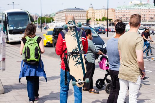 Urban life. Tourists with backpack and longboard on the street