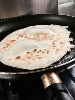 Black big old and dirty pan with fresh and tasty pancake.