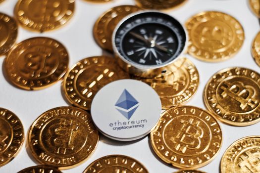 Digital currency physical grey Ethereum coin near gold bitcoins.