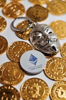 Digital currency physical grey Ethereum coin near gold bitcoins.