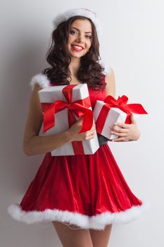 Excited surprised woman in red santa claus outfit holding Christmas presents