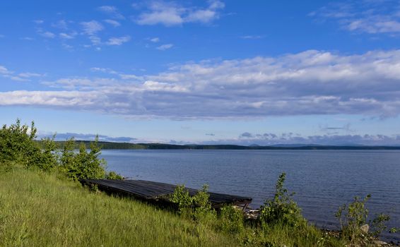 quiet lake Uvildy early in the morning, clear water, clear bottom, South Ural, in the distance are seen the Ural mountains