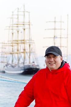 Big fat man in red jacket on ship background