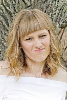 Portrait of disgruntled girl with blue eyes on wood background