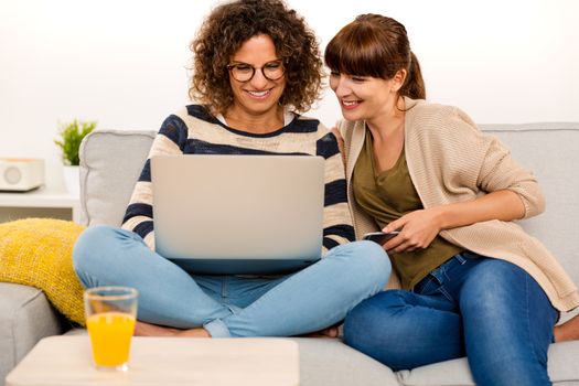 Two beautiful women at home working with a laptop