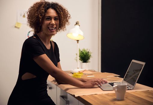 A young fashion designer on her atelier working with a laptop