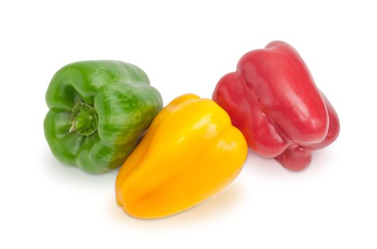 Green, yellow and red freshly harvested bell peppers on a white background closeup
