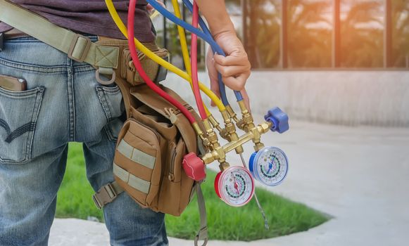 Man's hand holding a manometers on equipment for filling air conditioners