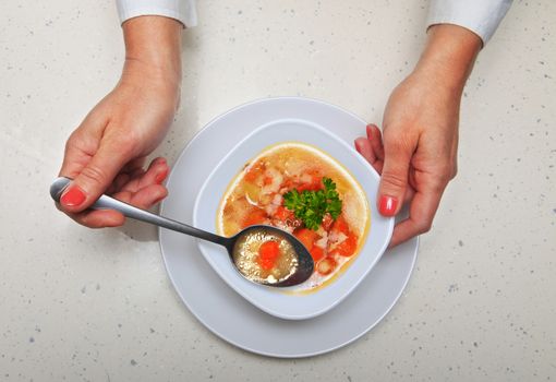 hands of woman who holds spoon with soup
