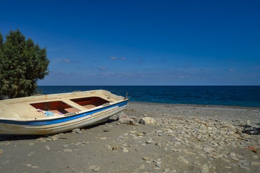 View of the pebble beach of Maleme with a boat abandon in the north west of the island of Crete in Greece