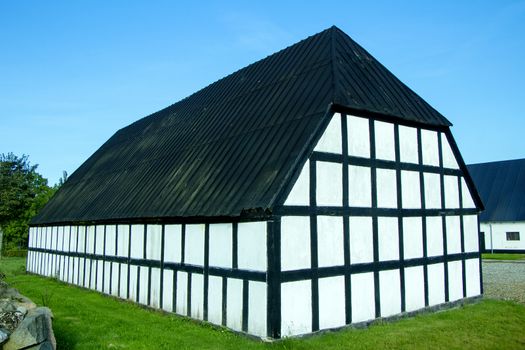 Black and white half timbered house with blue sky and green grass on a sunny day.