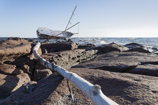 Sailboat, stranded along the coast on the cliff of Sardinia in the Mediterranean Sea.