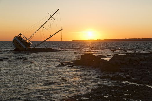 Sailboat, stranded along the coast on the cliff of Sardinia in the Mediterranean Sea.