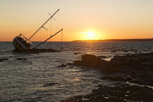 Sailboat, stranded along the coast on the cliff of Sardinia in the Mediterranean Sea.