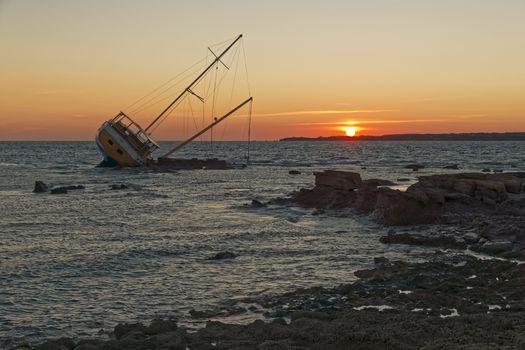 Sailboat, stranded along the coast on the cliff of Sardinia in the Mediterranean Sea.