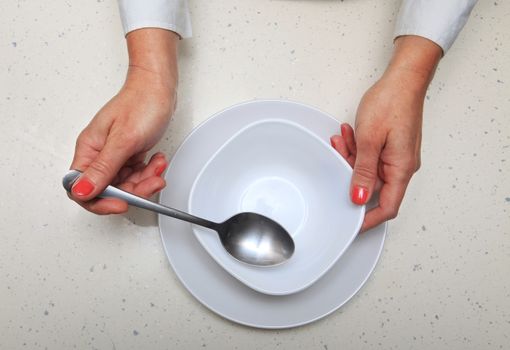 hands of woman who holds spoon and plate