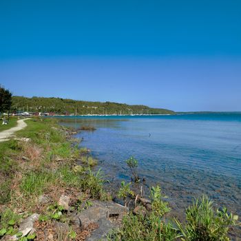 Panorama of the lake with yachts on the quay near a mountain covered with forest