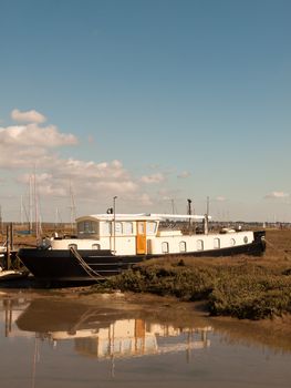 parked moored white and black boat in dockland marshland; essex; england; UK