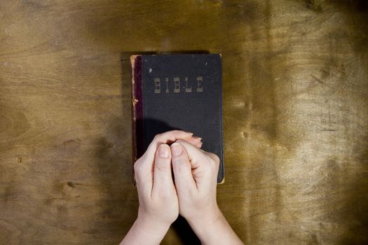 Hands of an unrecognizable woman with Bible praying