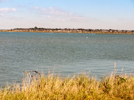 beautiful sea wave scene with village on other shore; essex; england; UK