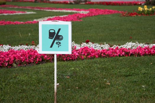 Sign board on the park lawn, asking not to pick up the flowers. Please do not step in the grass