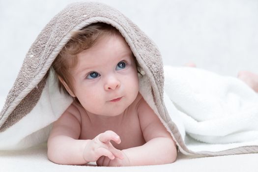 Cute baby after bath, parental care concept. Happy baby having fun. Three-months old baby looking up.
