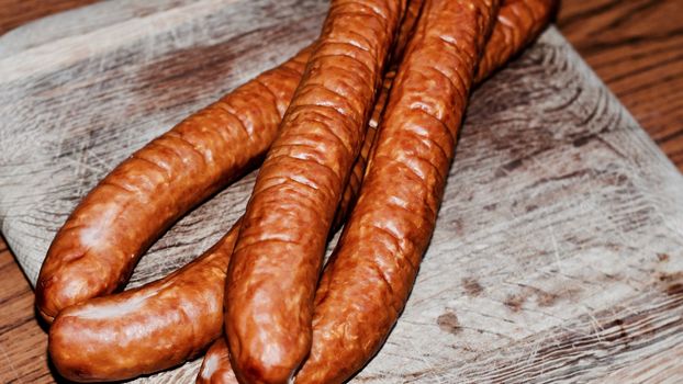Fresh and tasty sausages on the wooden board. BBQ concept.