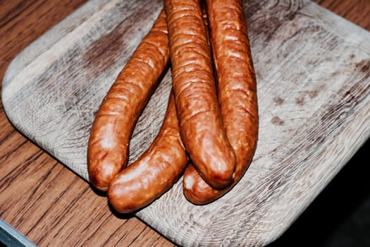 Fresh and tasty sausages on the wooden board. BBQ concept.