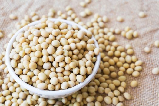 Closeup soy beans on white bowl with sackcloth background , healthy food concept