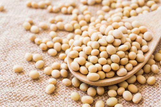 Closeup soy beans on wood spoon with sackcloth background , healthy food concept