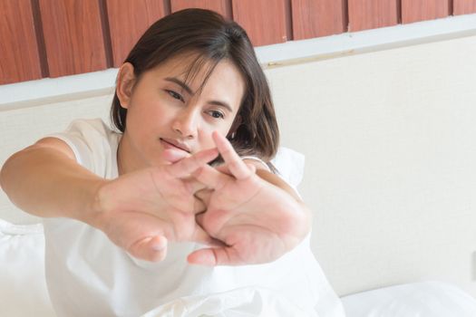 Closeup woman stretching hand on her bed after waking in the morning, selective focus